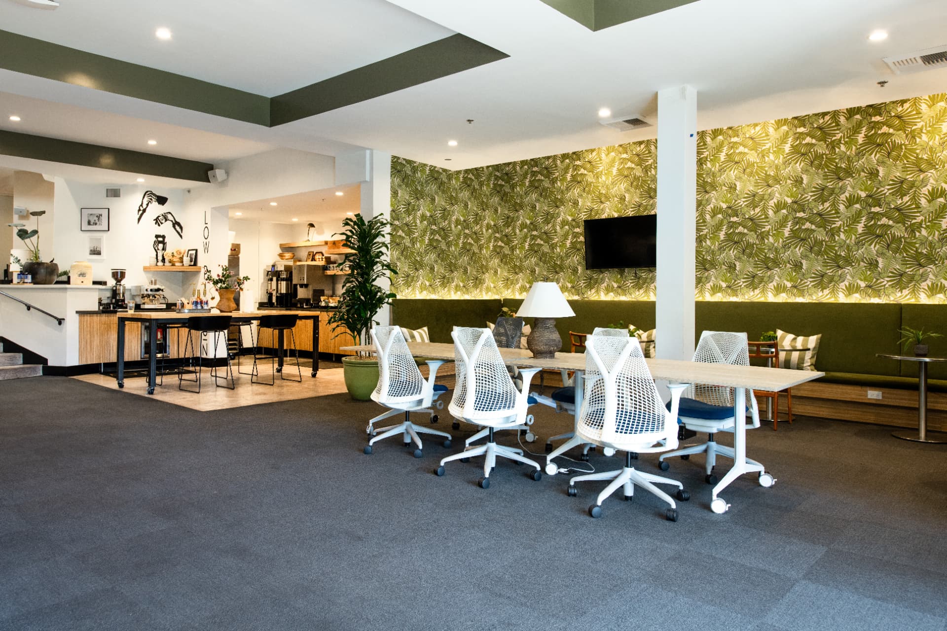 Coworking lounge at Kiva State St. with a long communal table, green banquette seating and a coffee bar